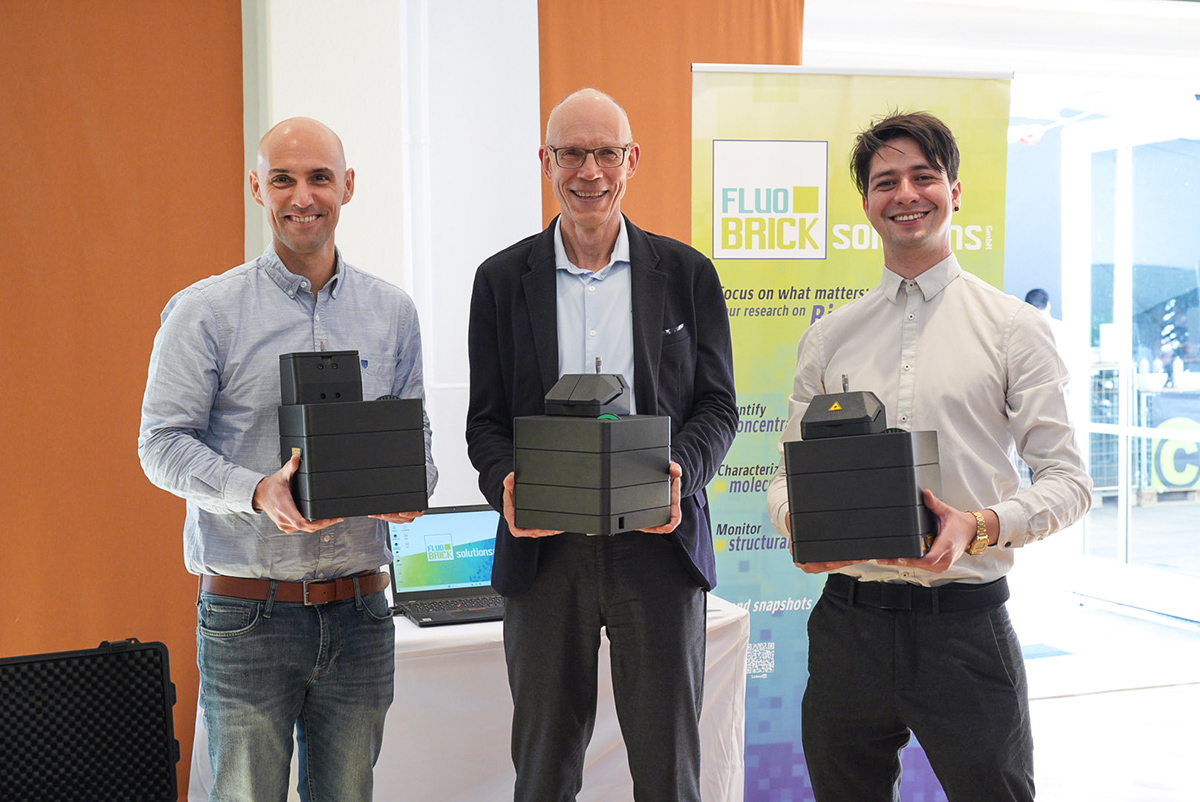 Rainer Erdmann from PicoQuant (middle), Dr. Gabriel Moya (right) and Prof. Dr. Thorben Cordes (left) from FluoBrick Solutions seal their partnership to jointly foster innovation in single-molecule research.